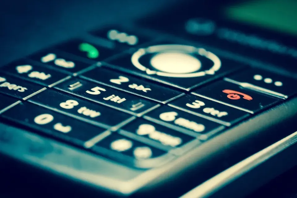 Close-up of the keypad of an old mobile phone in blue-green light