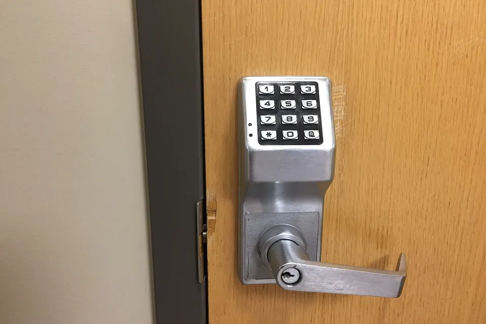 A keypad lock with a lever handle on a wooden door